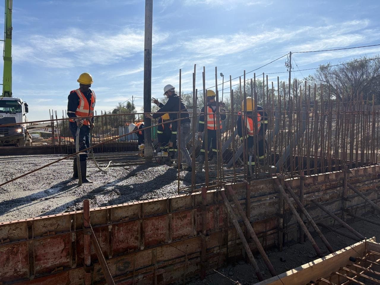Crew fixing reinforcement to a wall starter on a foundation